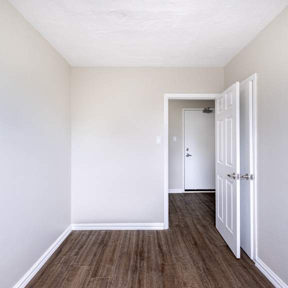 a room with a white door and brown flooring.