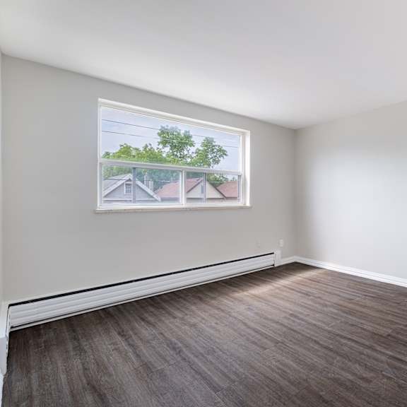 a room with a large window and wooden flooring.
