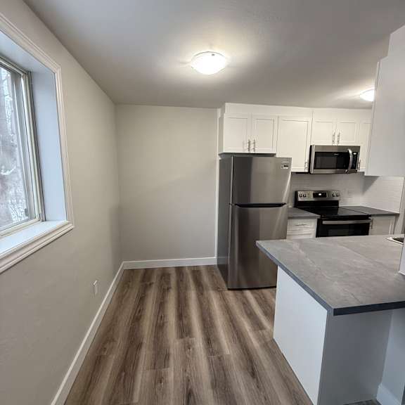 a modern kitchen with a stainless steel refrigerator and wooden wall paneling.