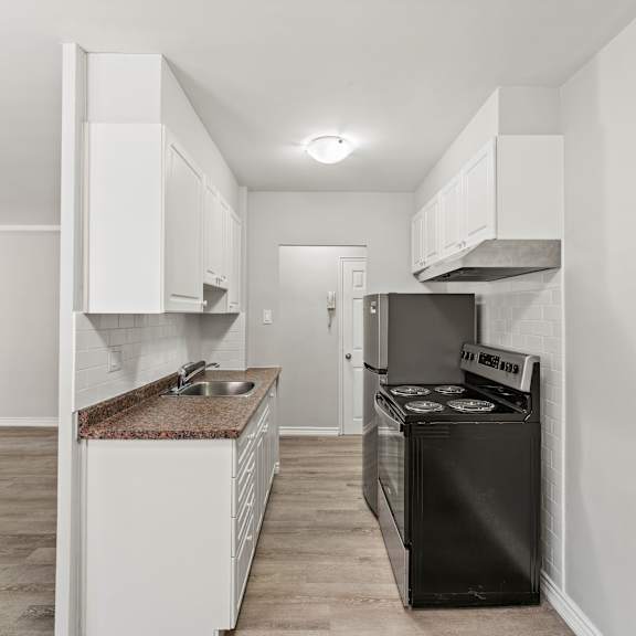 a kitchen with white cabinets and a black dishwasher.
