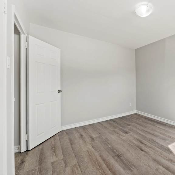 a room with a white door and wooden flooring.