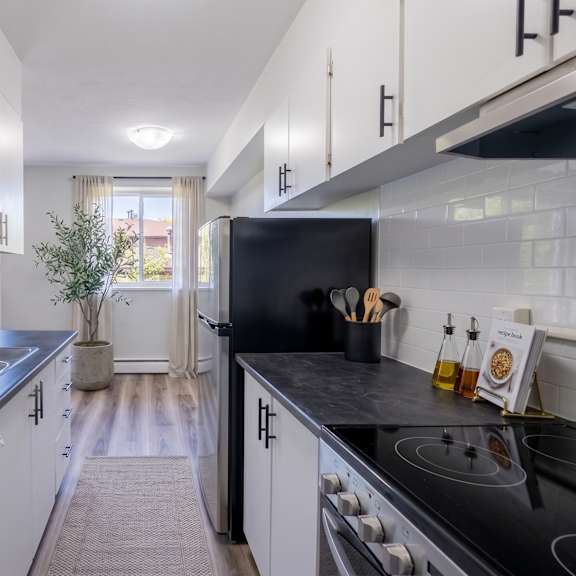 a modern kitchen with black countertops and white cabinets.