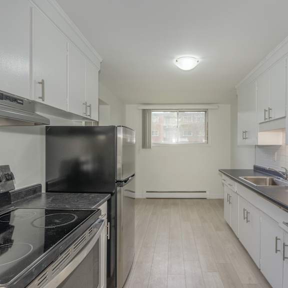 a kitchen with white cabinets and black countertops.