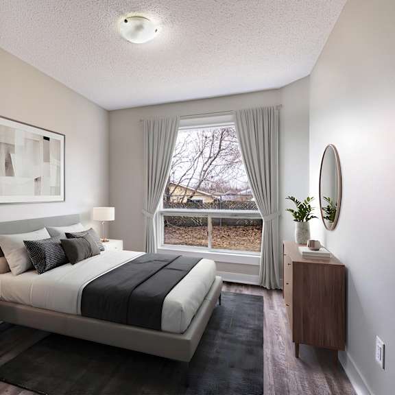 a well-lit bedroom with a large bed and a window with curtains.