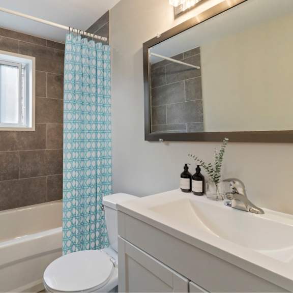 a bathroom with a white toilet, a white sink, a bathtub, and a shower curtain.