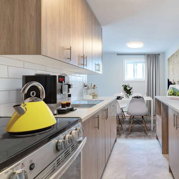 a modern kitchen with a yellow kettle on the stove.