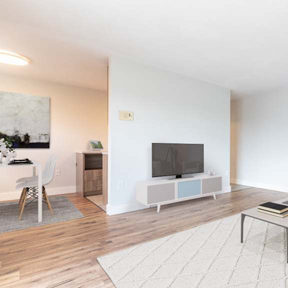 a living room with a white couch, a coffee table, a television, and a painting on the wall.