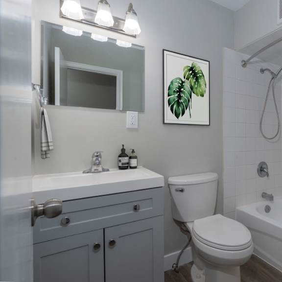 a bathroom with a toilet, sink, and shower.