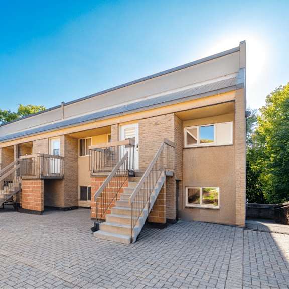 a sunny day at a brick building with a staircase leading to the entrance.