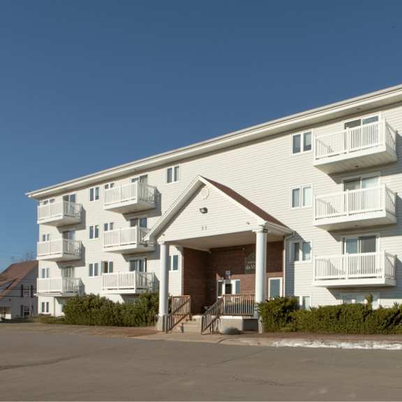 a large white apartment building with balconies and a covered entrance.