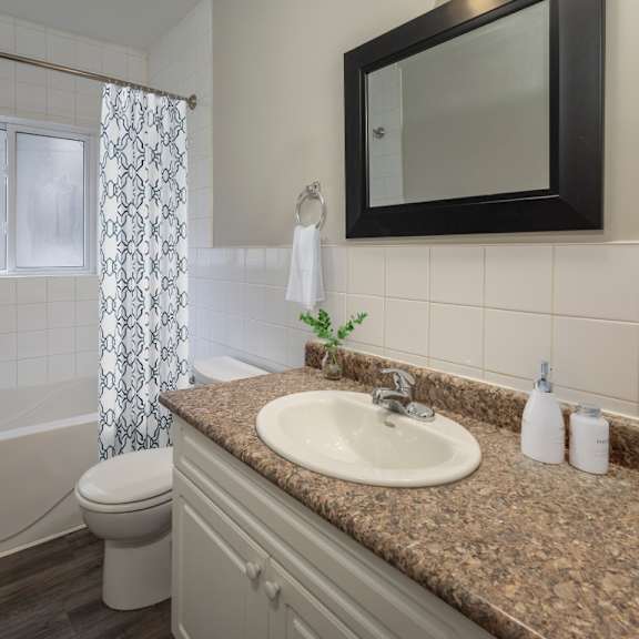 a bathroom with a brown granite countertop and a white toilet.