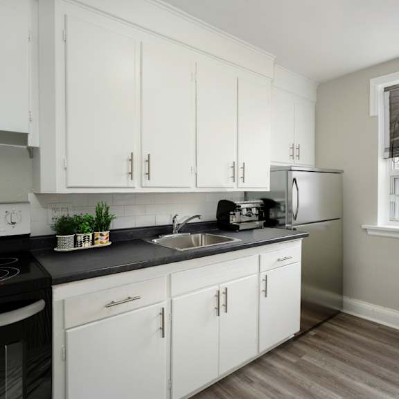 a kitchen with white cabinets and a black countertop.