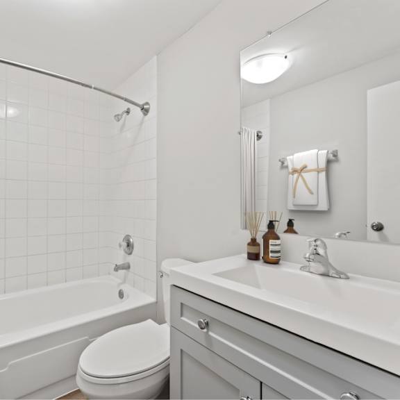 a white bathroom with a toilet, sink, and shower.