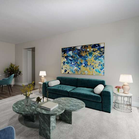 a living room with a green couch and a painting on the wall.
