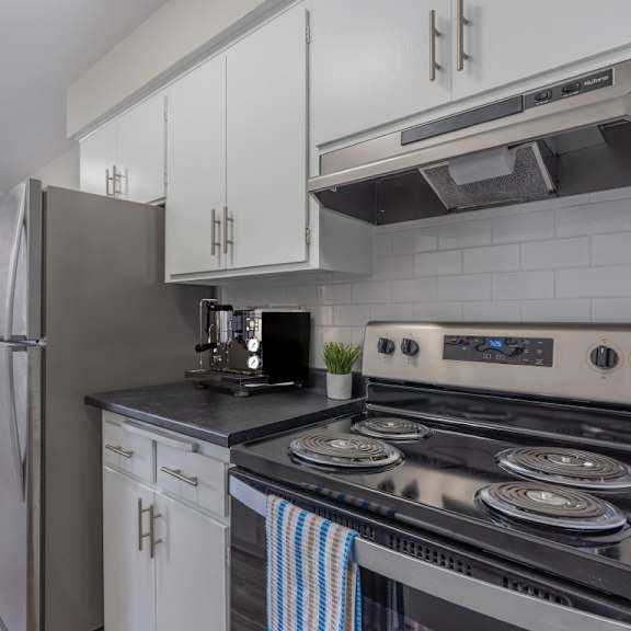 a kitchen with a stove, refrigerator, and cabinets.