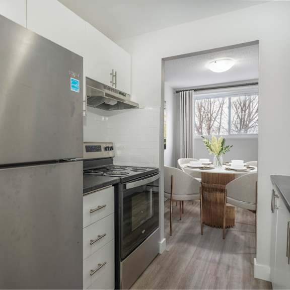 a modern kitchen with a stainless steel refrigerator and a dining table set for two.