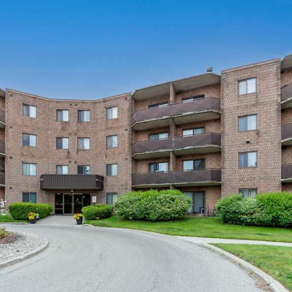 a large brick apartment building with a driveway in front.
