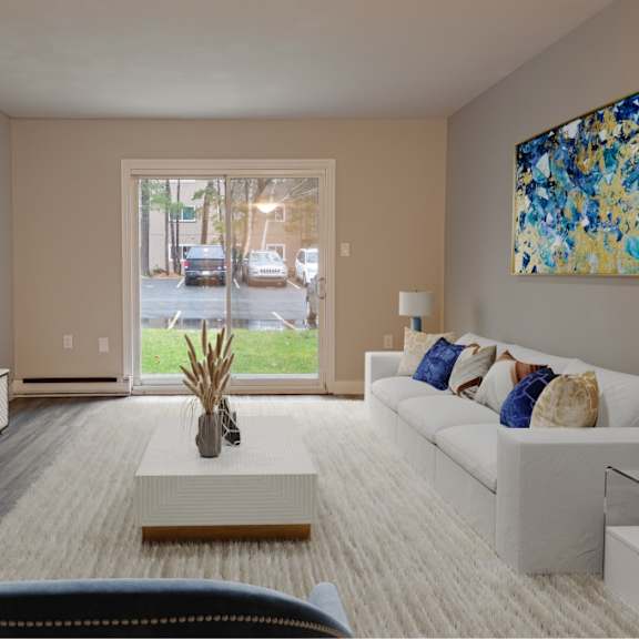 a living room with a white couch, a television, and a painting on the wall.