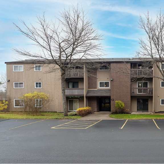 a large apartment complex with a parking lot in front.