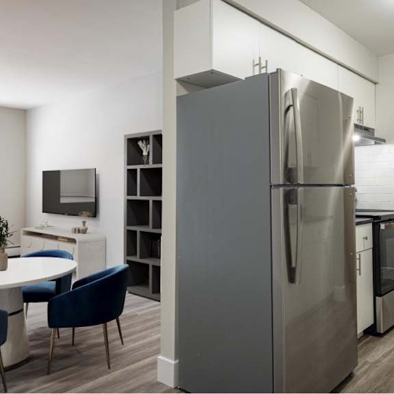 a modern kitchen with a large refrigerator and a dining table with chairs.