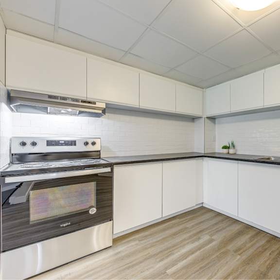 a modern kitchen with a stove and white cabinets.
