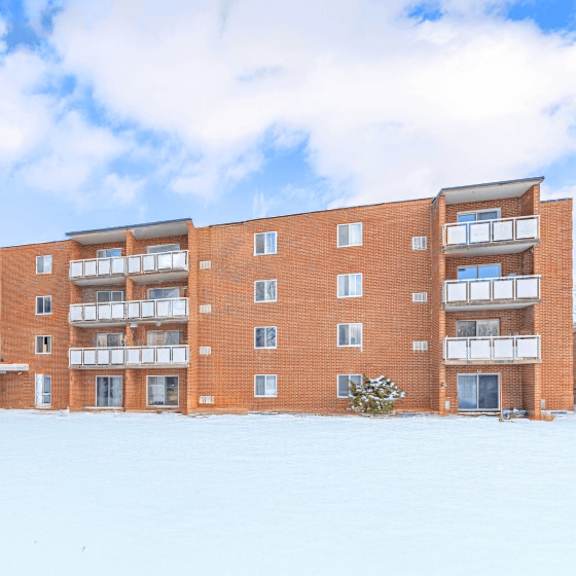 a red brick building with a snowy ground in front.