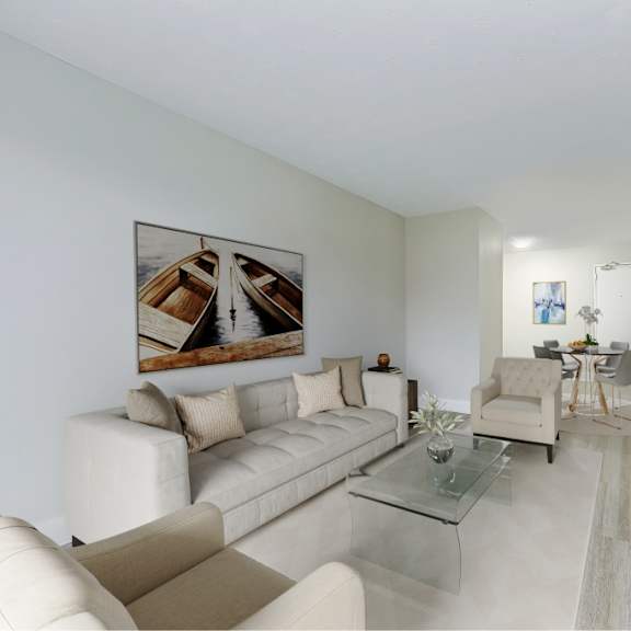 a living room with a white couch, a glass coffee table, and a painting on the wall.