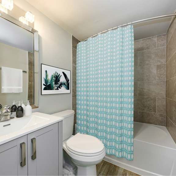 a bathroom with a white toilet, sink, and shower curtain.