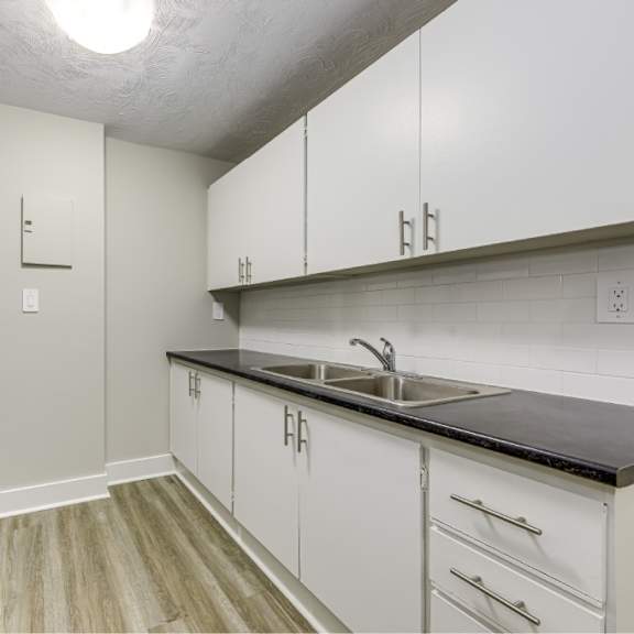 a kitchen with white cabinets and a black counter top.