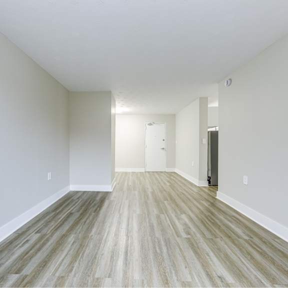 a long, empty hallway with wood flooring and white walls.