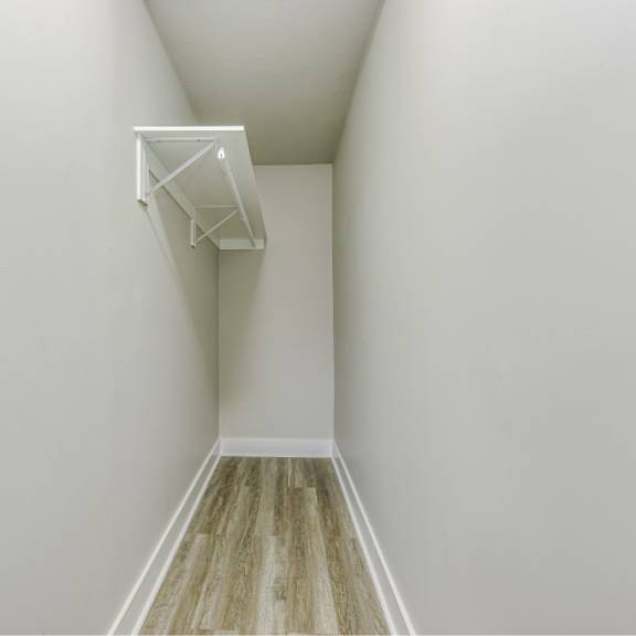 a white room with a wooden floor and a white shelf on the wall.