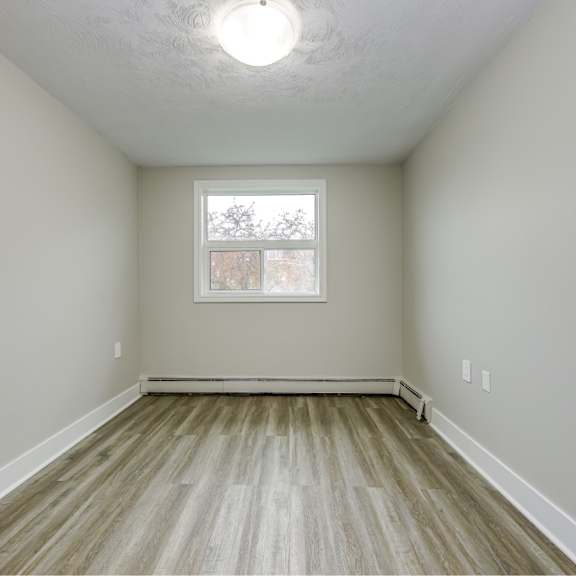 a room with a window and wooden flooring.