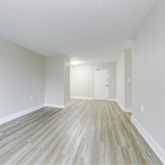 a long, empty hallway with wood flooring and white walls.