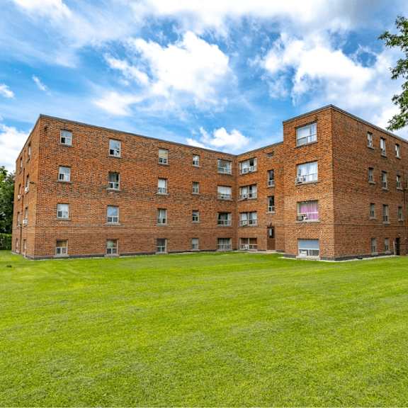 a large red brick building with a green lawn in front.