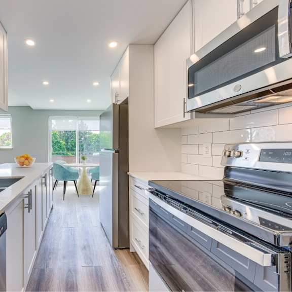 a modern kitchen with white cabinets and stainless steel appliances.