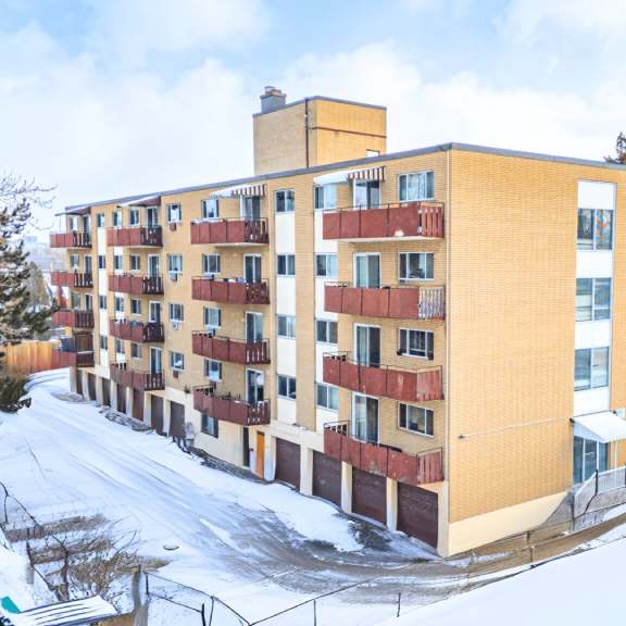 a large apartment building with a snowy landscape in front.