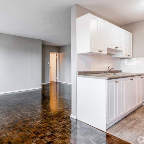 a kitchen with white cabinets and a wooden floor.