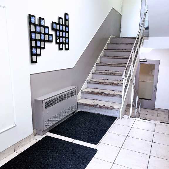 a staircase with a metal railing and a wall with black squares on it.