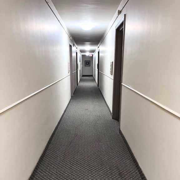 a long, narrow hallway with a carpeted floor and white walls.