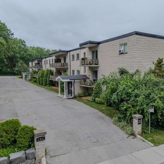 apartment complex with a driveway and greenery.