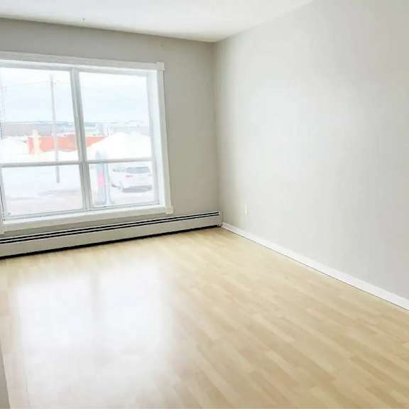 a room with a large window and wooden flooring.