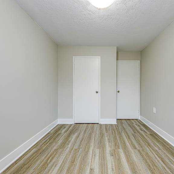a room with two white doors and wooden flooring.
