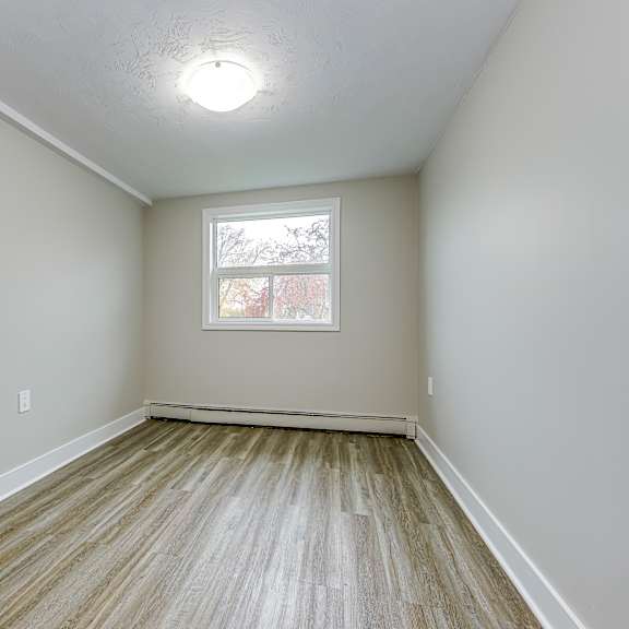 a room with a window and wooden flooring.