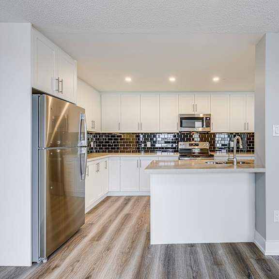 a modern kitchen with a stainless steel refrigerator and white cabinets.