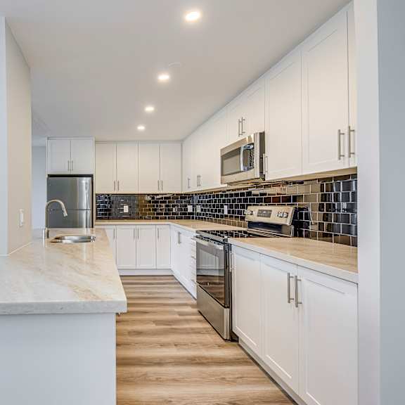 a kitchen with white cabinets and a marble countertop.