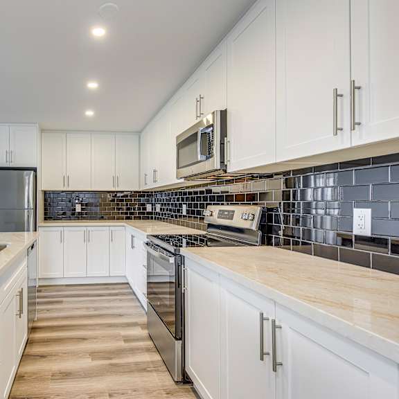 a kitchen with white cabinets and a marble countertop.