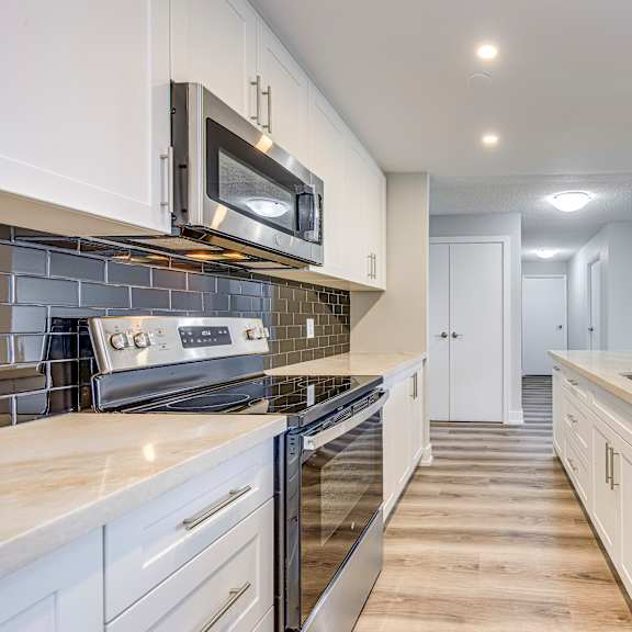 a modern kitchen with white cabinets and stainless steel appliances.