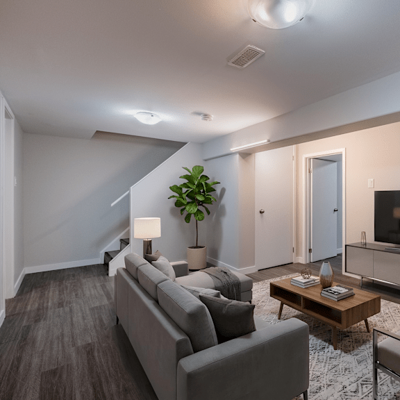 a living room with a grey couch, a wooden coffee table, and a television.