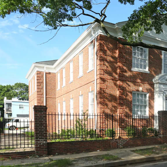 a red brick building with a black iron fence in front.