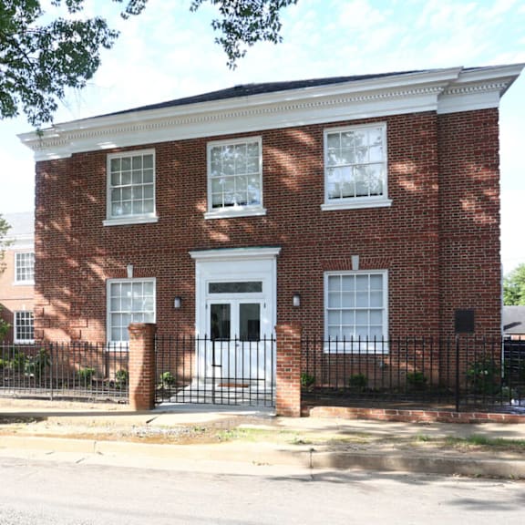 a brick building with a black gate in front.